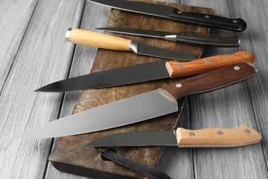 Photo of Many different knives and board on light wooden table