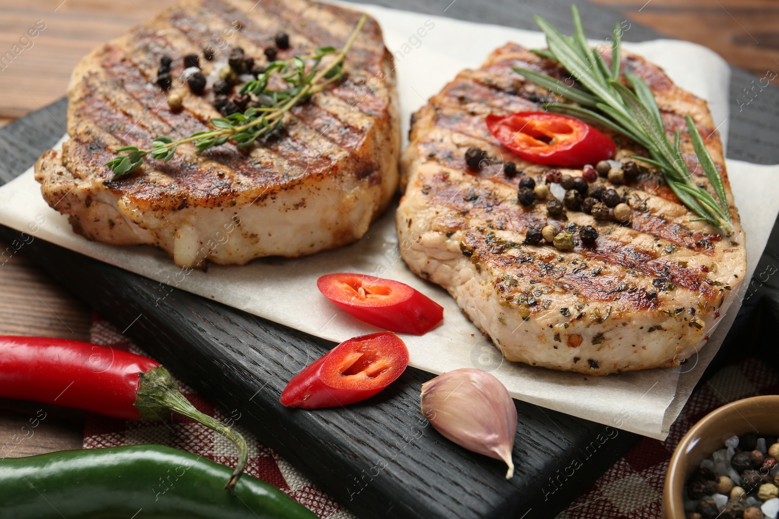 Photo of Delicious grilled pork steaks with spices on table, closeup