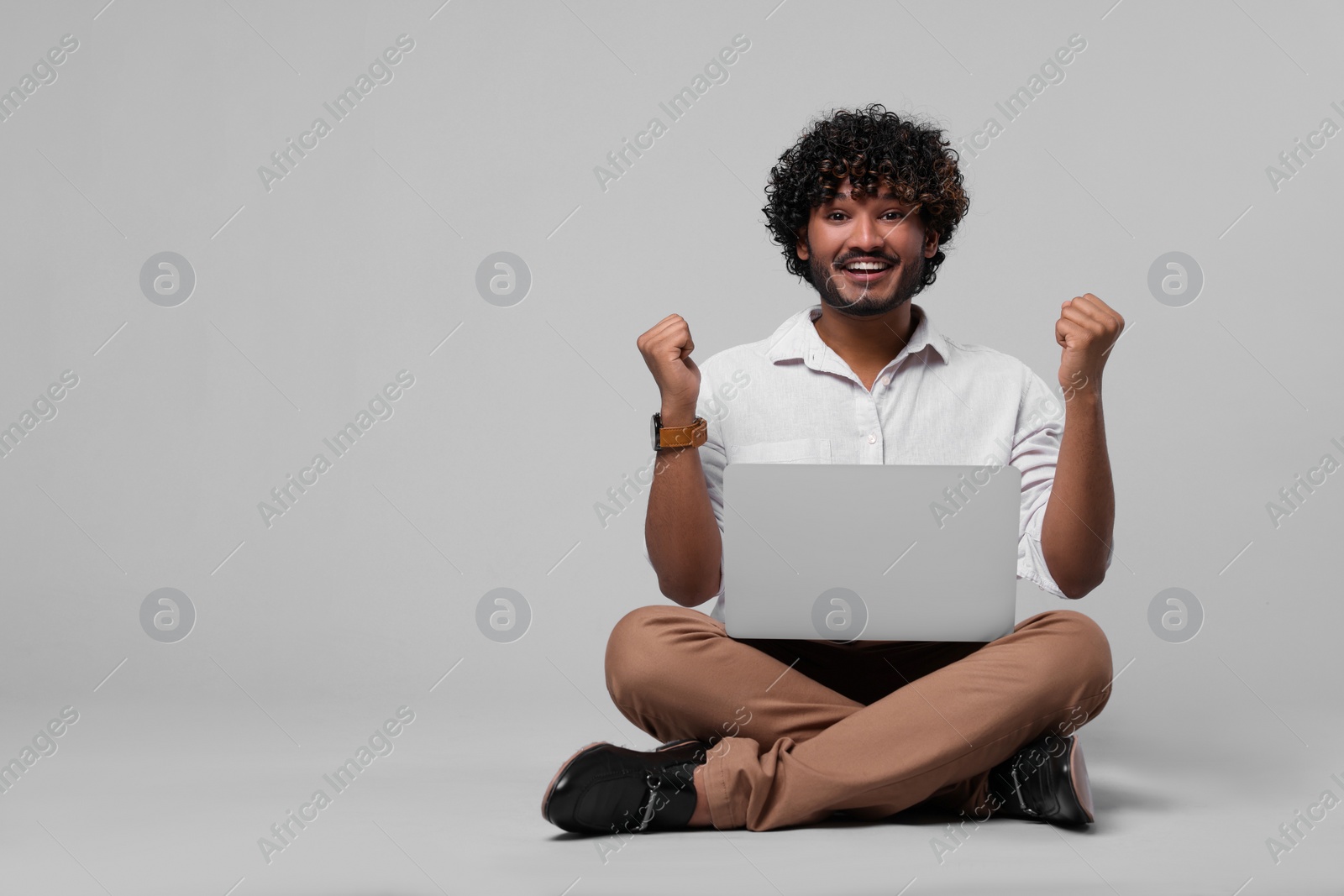 Photo of Emotional man with laptop on light grey background, space for text