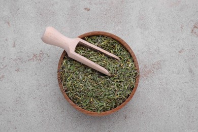Bowl and scoop with dried thyme on grey table, top view