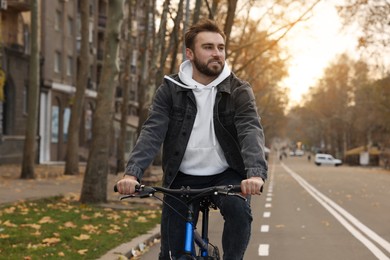 Photo of Happy handsome man riding bicycle on lane in city