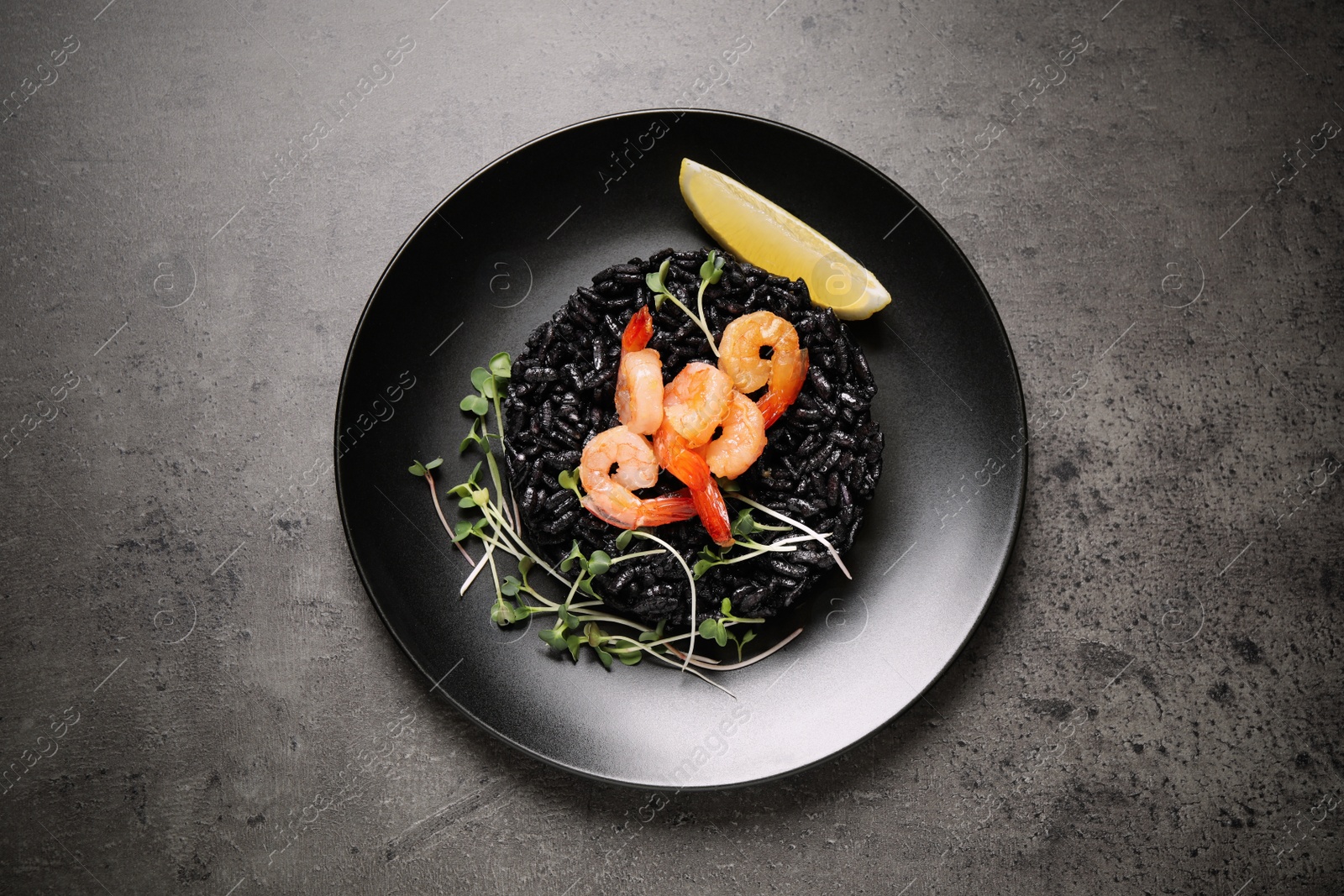 Image of Delicious black risotto with shrimps and lemon on grey table, top view. Food photography  