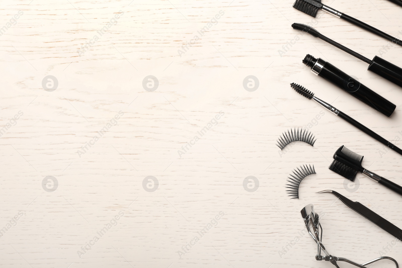 Photo of Artificial eyelashes and accessories on wooden background, top view with space for text