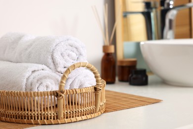 Photo of Rolled soft towels on white table in bathroom. Space for text