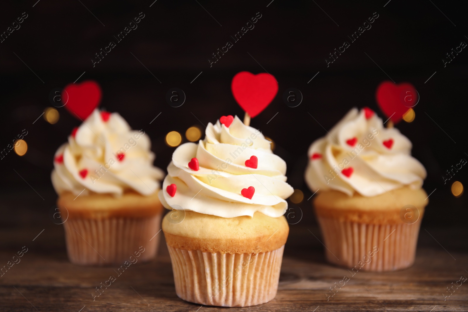 Photo of Tasty sweet cupcakes on wooden table. Happy Valentine's Day