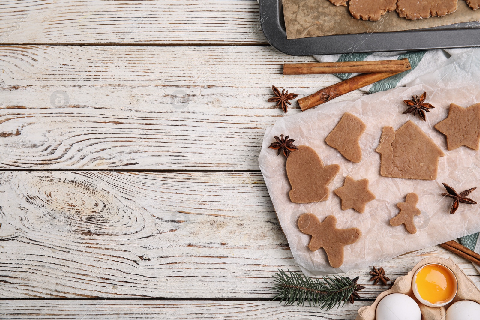 Photo of Making Christmas cookies. Flat lay composition with raw dough and ingredients on white wooden table, space for text
