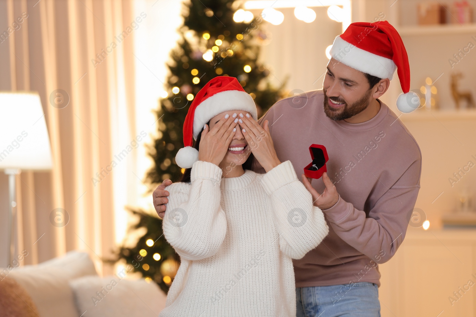 Photo of Making proposal. Man with engagement ring surprising his girlfriend at home on Christmas