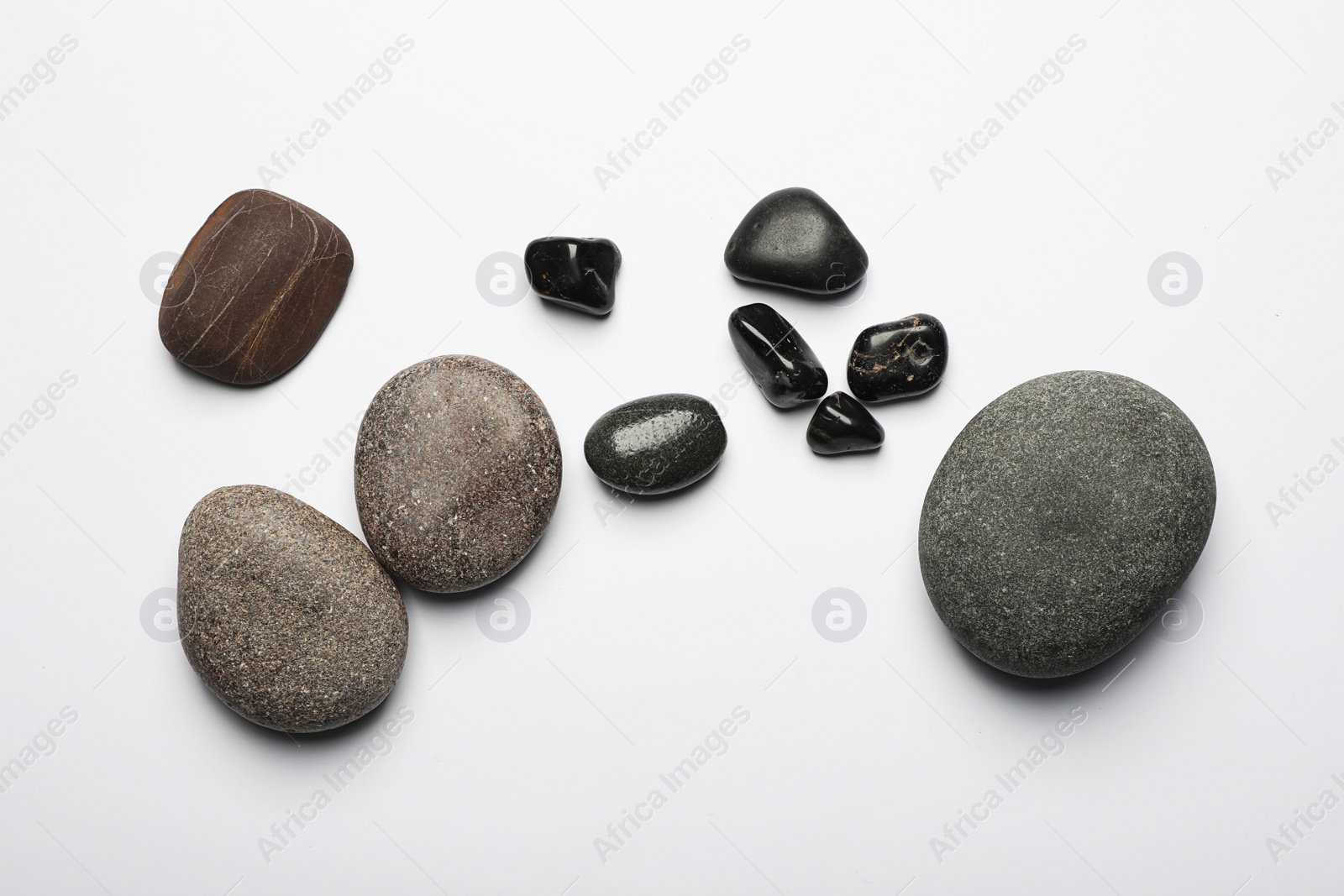 Photo of Many different stones on white background, top view