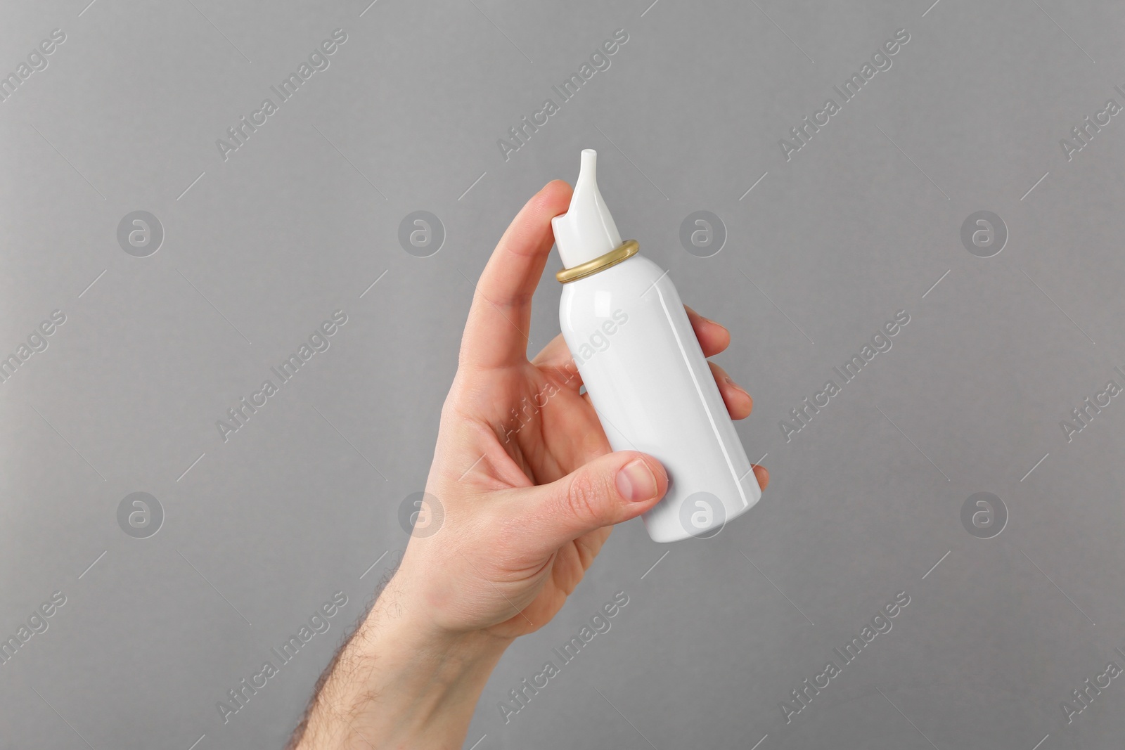 Photo of Man holding nasal spray on light grey background, closeup