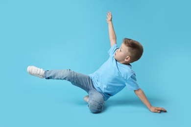 Happy little boy dancing on light blue background