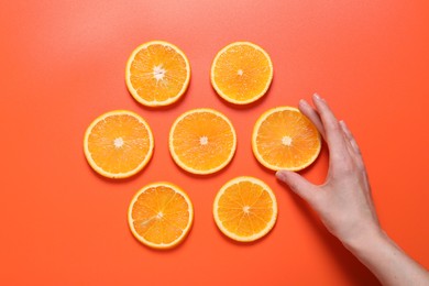 Photo of Woman with slices of juicy orange on terracotta background, top view