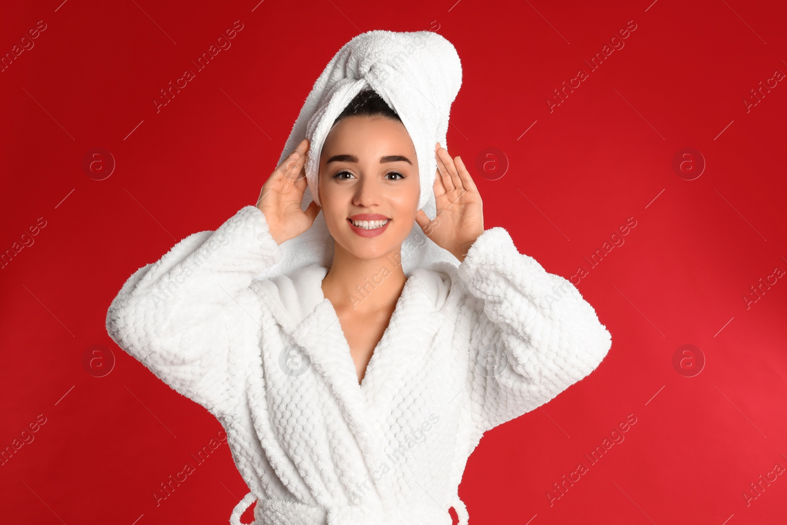 Photo of Beautiful young woman in bathrobe on red background