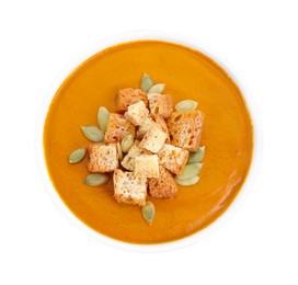 Photo of Delicious pumpkin cream soup with seeds and croutons in bowl isolated on white, top view