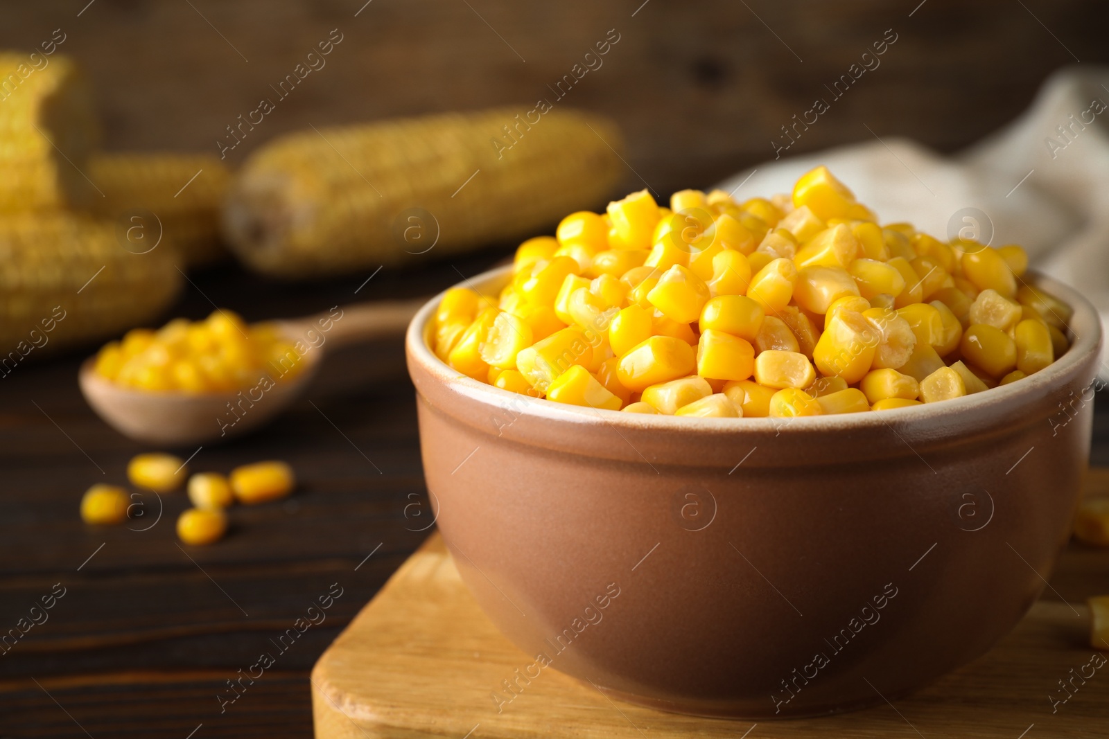 Photo of Delicious canned corn in bowl on wooden table, closeup