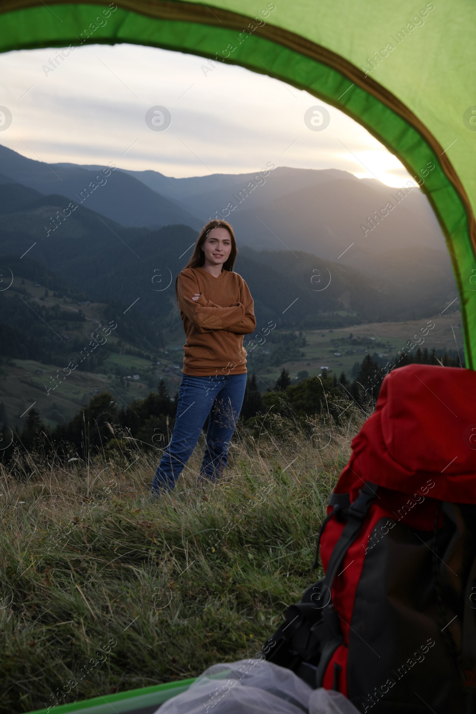 Photo of Young woman in mountains, view from camping tent