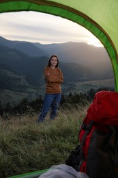 Young woman in mountains, view from camping tent