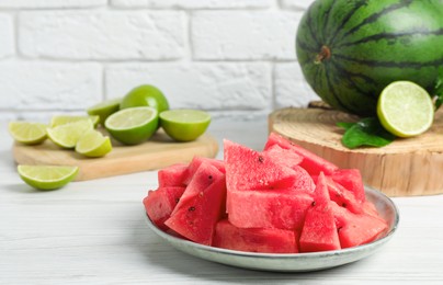 Slices of delicious watermelon and limes on white wooden table