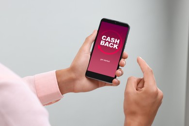 Image of Man using smartphone with word Cashback on blurred background, closeup