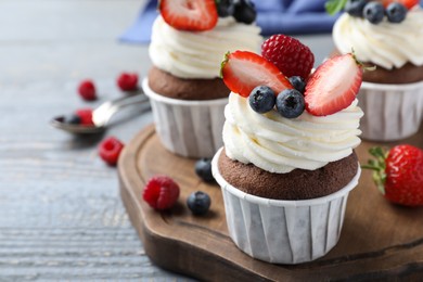 Photo of Sweet cupcakes with fresh berries on wooden table, closeup