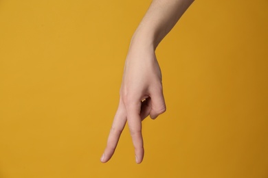 Woman imitating walk with hand on yellow background, closeup. Finger gesture