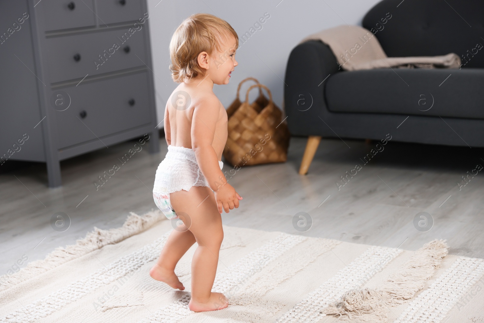 Photo of Cute baby learning to walk in living room