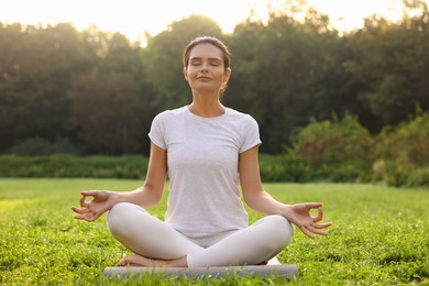 Beautiful woman practicing yoga on mat outdoors. Lotus pose