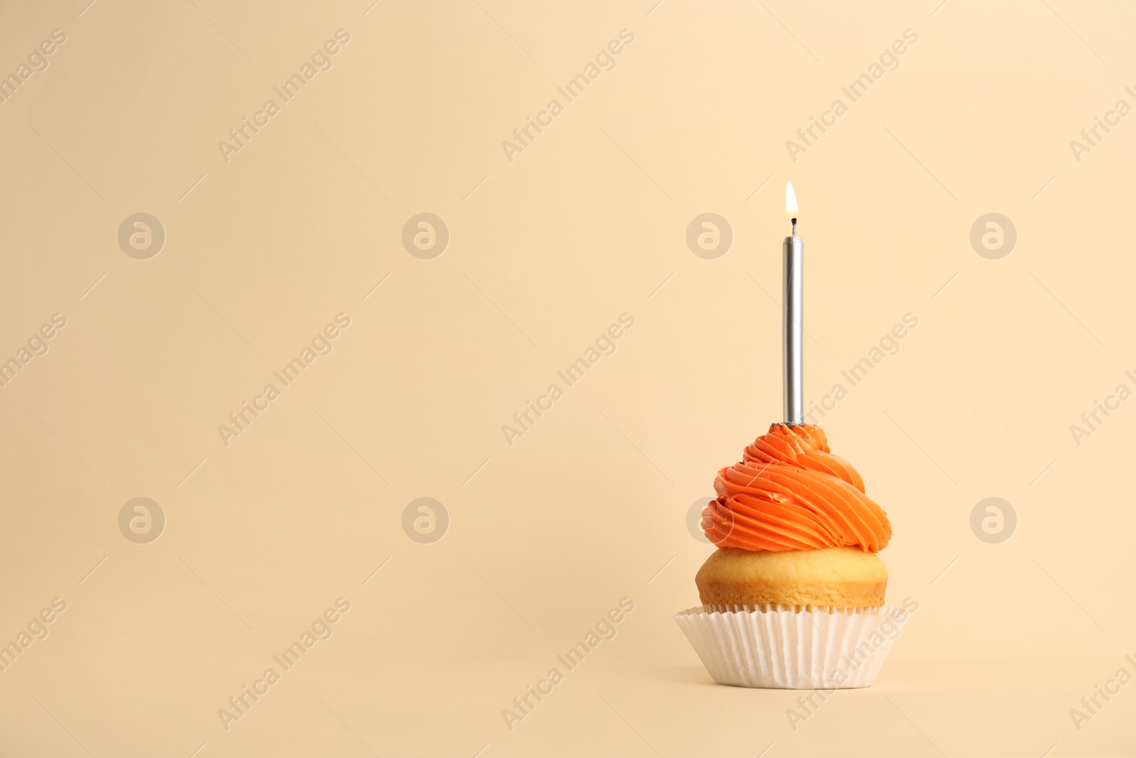 Photo of Birthday cupcake with candle on beige background, space for text