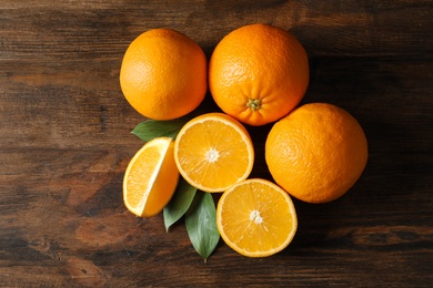 Fresh oranges with leaves on wooden background, top view