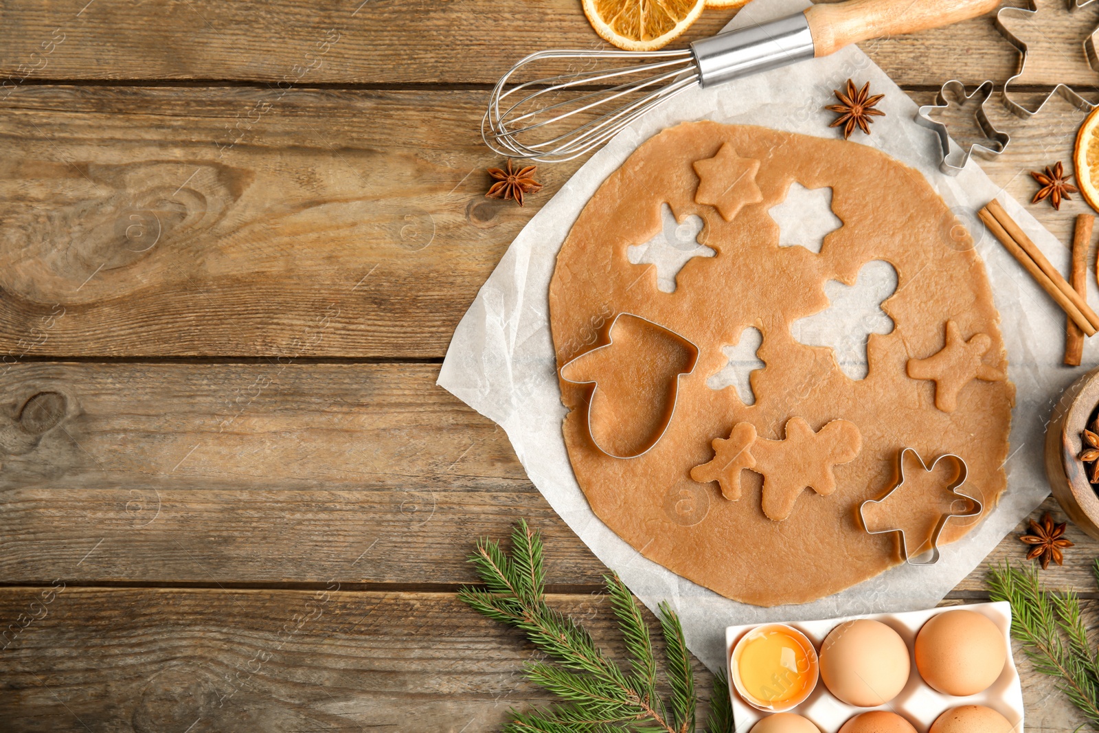 Photo of Flat lay composition with dough and cookie cutters on wooden table, space for text. Christmas biscuits