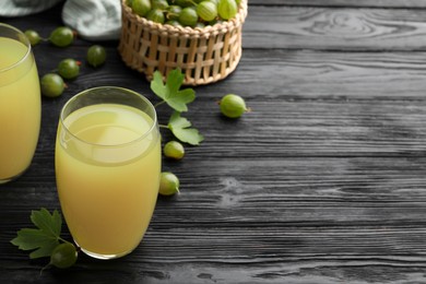 Photo of Tasty gooseberry juice on black wooden table. Space for text