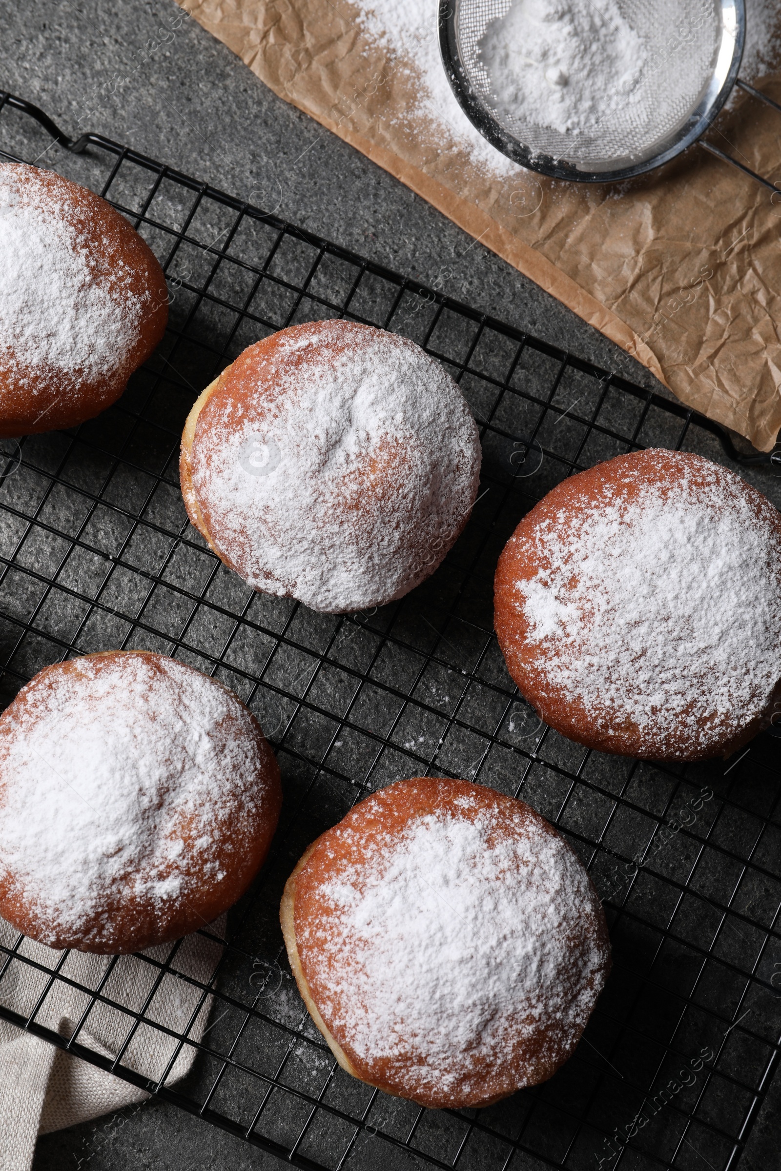Photo of Delicious sweet buns, powdered sugar and strainer on table, flat lay