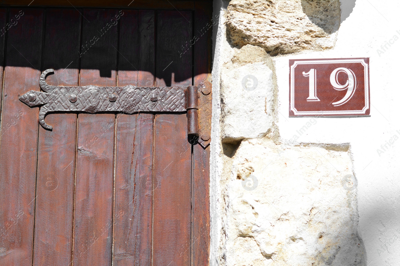 Photo of Plate with house number nineteen near door on stone wall outdoors