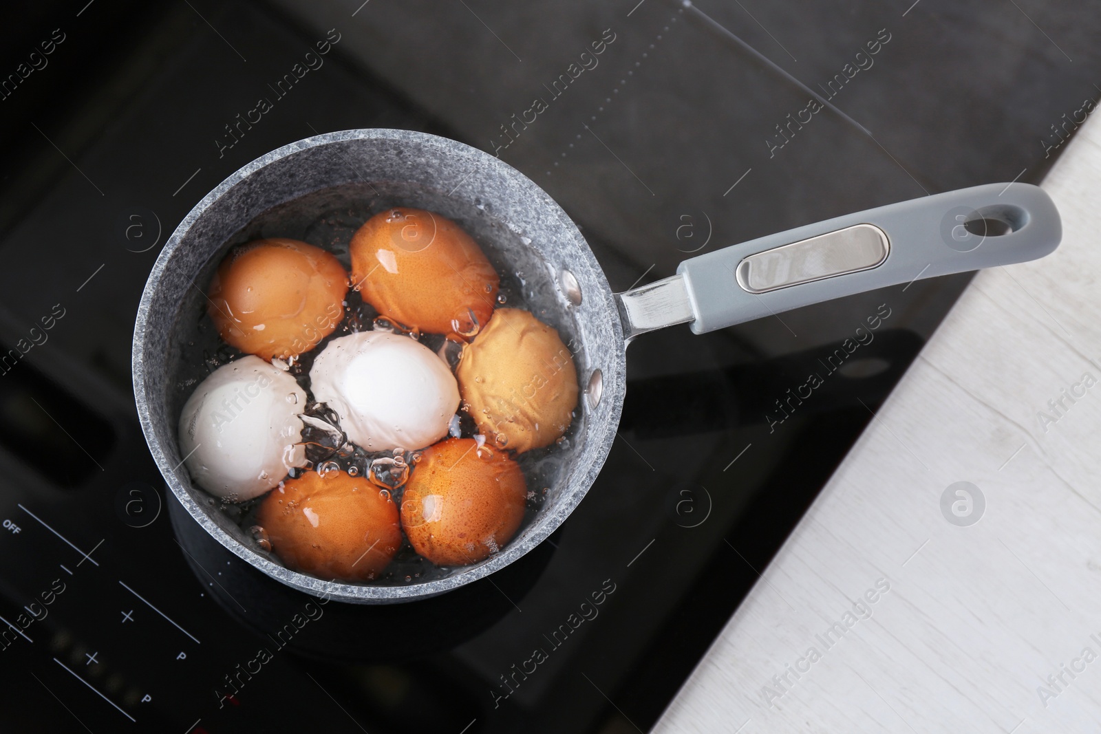 Photo of Chicken eggs boiling in saucepan on electric stove, top view