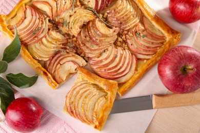 Photo of Tasty apple pie with nuts, knife and fresh fruits on table, flat lay