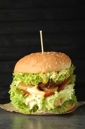 Photo of Burger with delicious patty on gray table against dark background