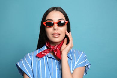 Photo of Fashionable young woman in stylish outfit with bandana on light blue background