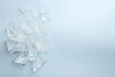 Photo of Pieces of crushed ice on light blue background, top view. Space for text