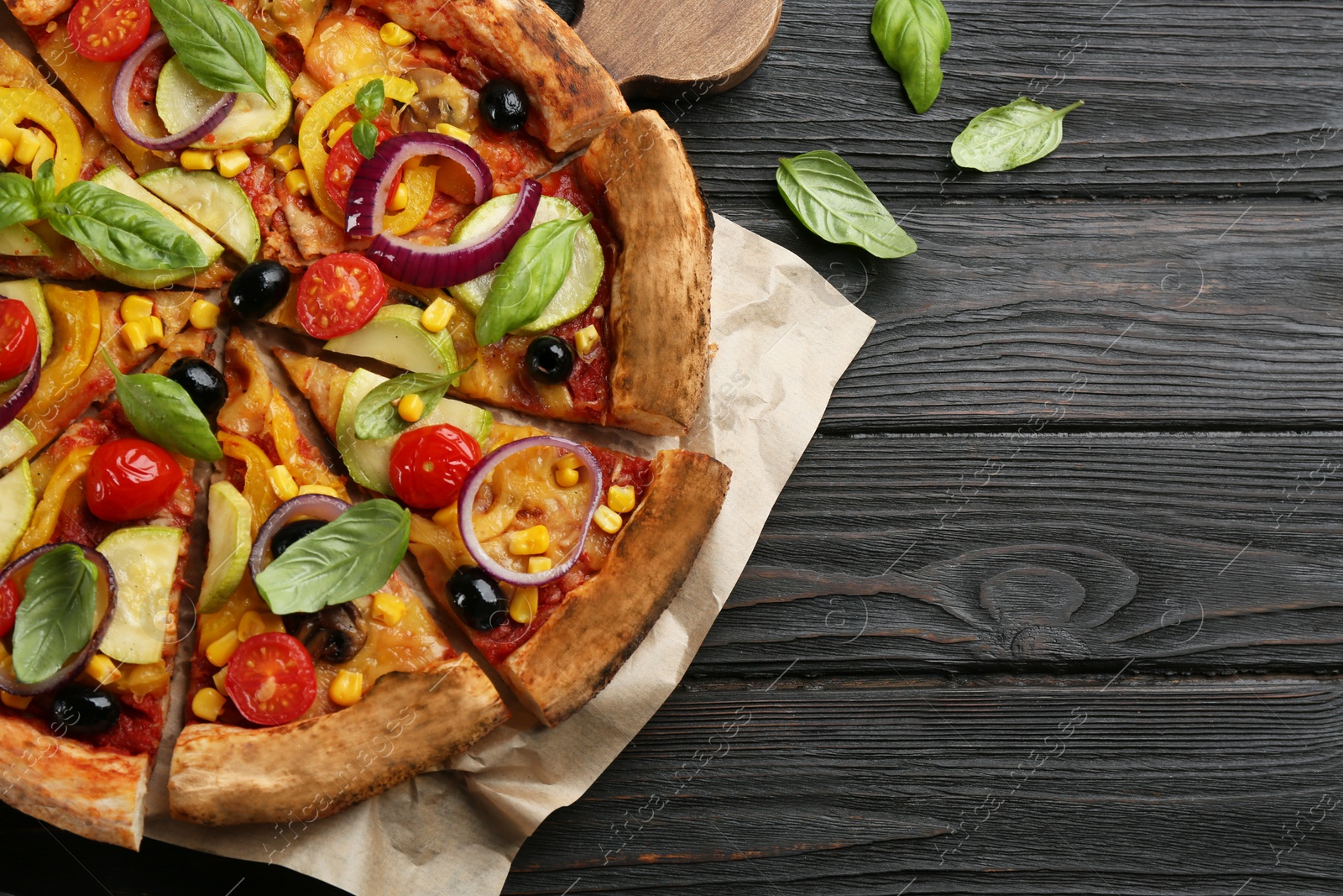 Photo of Tasty vegetable pizza on black wooden table, flat lay. Space for text
