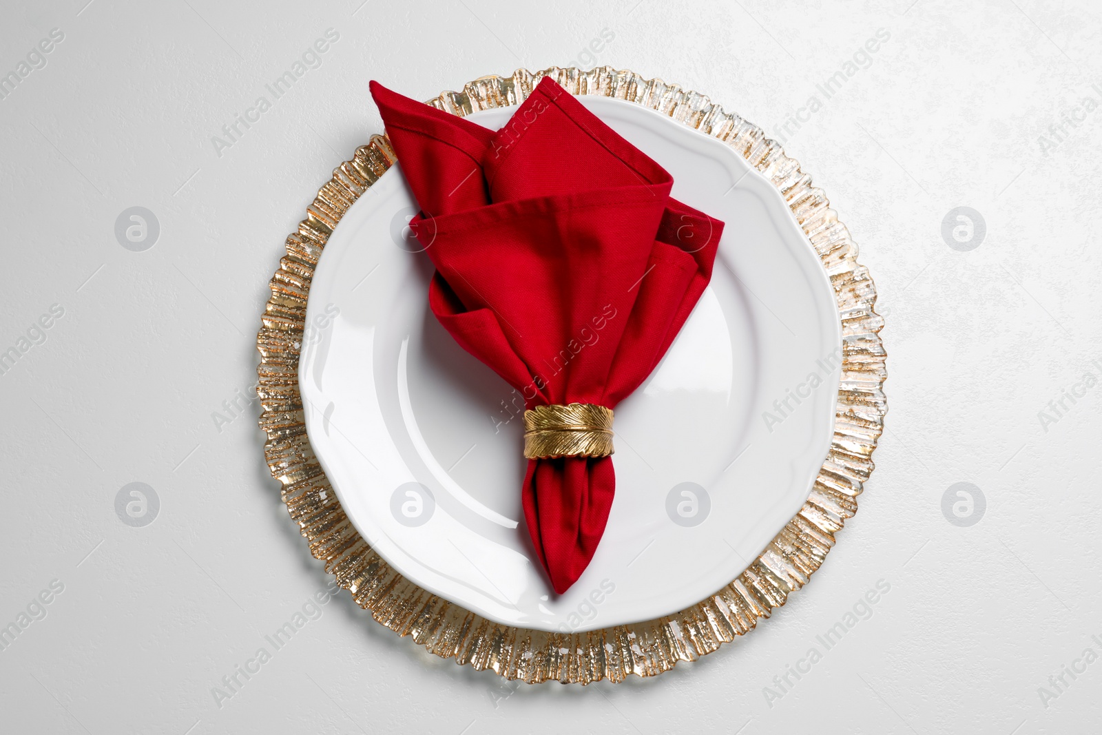 Photo of Plate with red fabric napkin and decorative ring on white table, top view