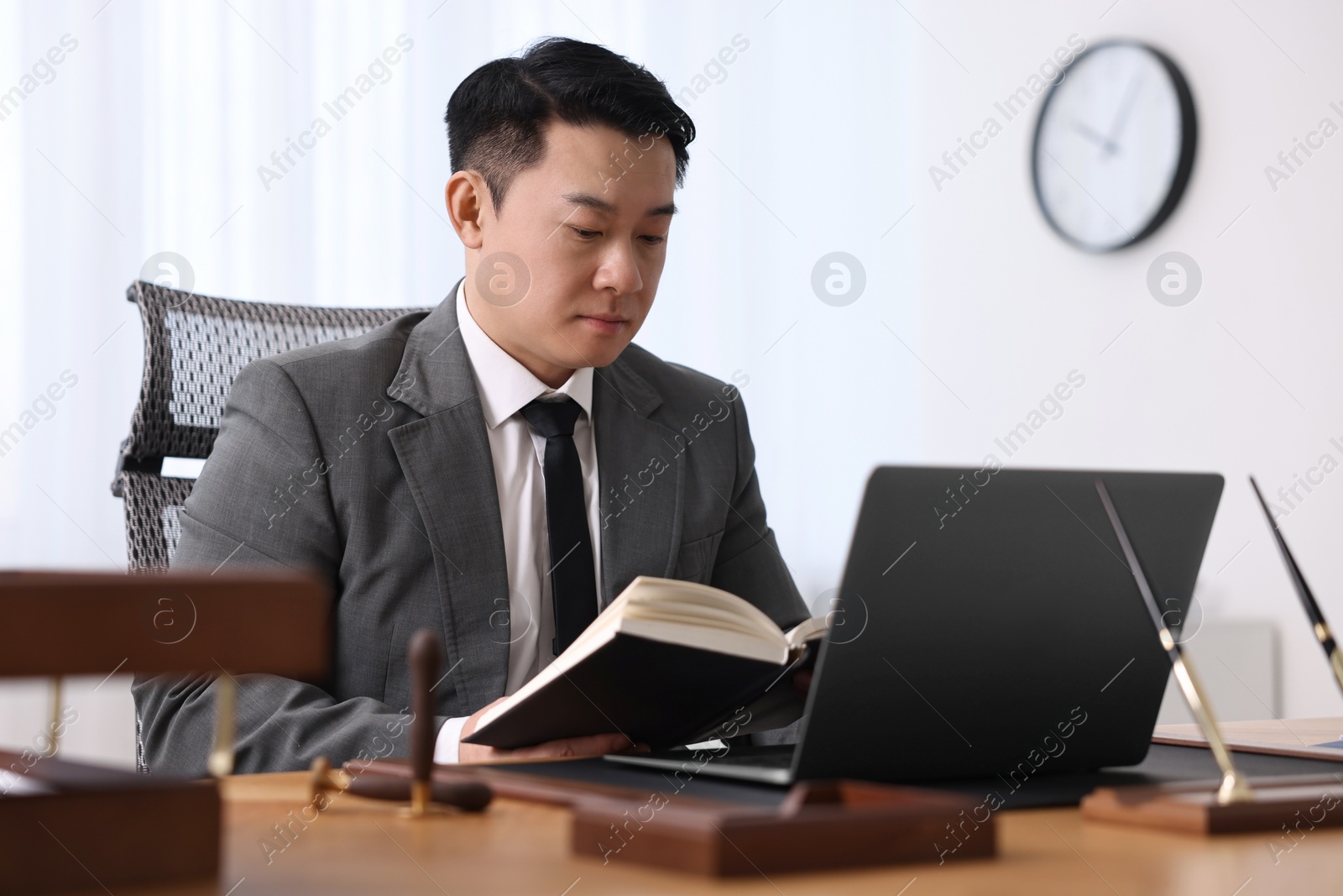 Photo of Notary working with laptop and book at wooden table in office