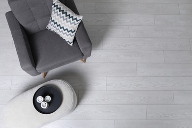 Photo of Stylish grey armchair and pouf with candles in room, top view. Interior design