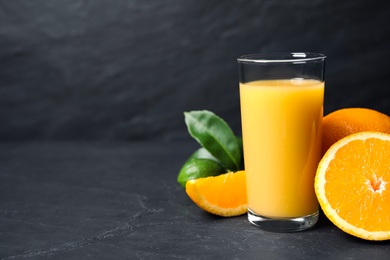 Glass of orange juice and fresh fruits on grey table. Space for text