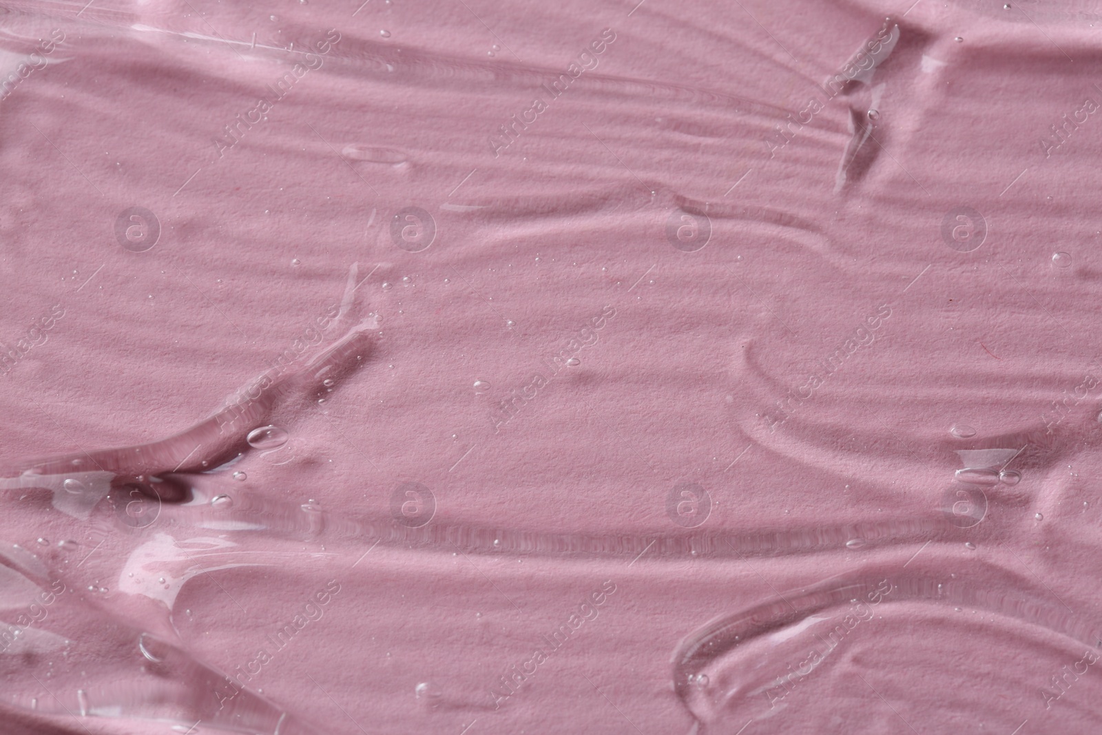 Photo of Clear cosmetic serum on pink background, macro view