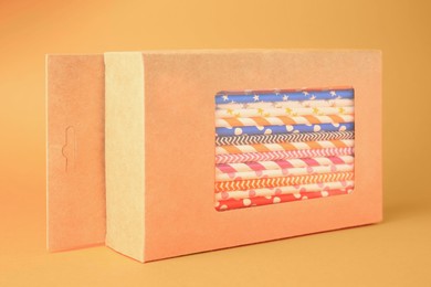 Photo of Box with many paper drinking straws on orange background
