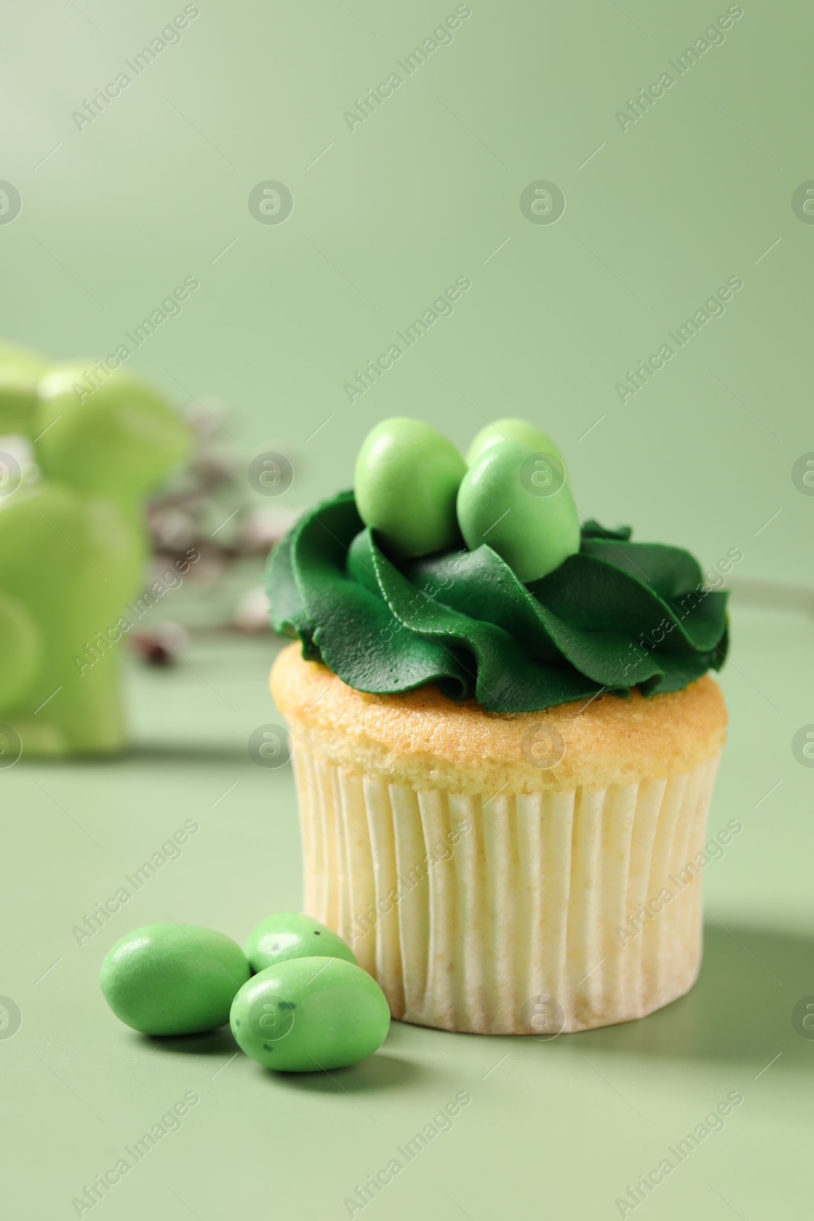 Photo of Tasty cupcake with Easter decor on green background, closeup