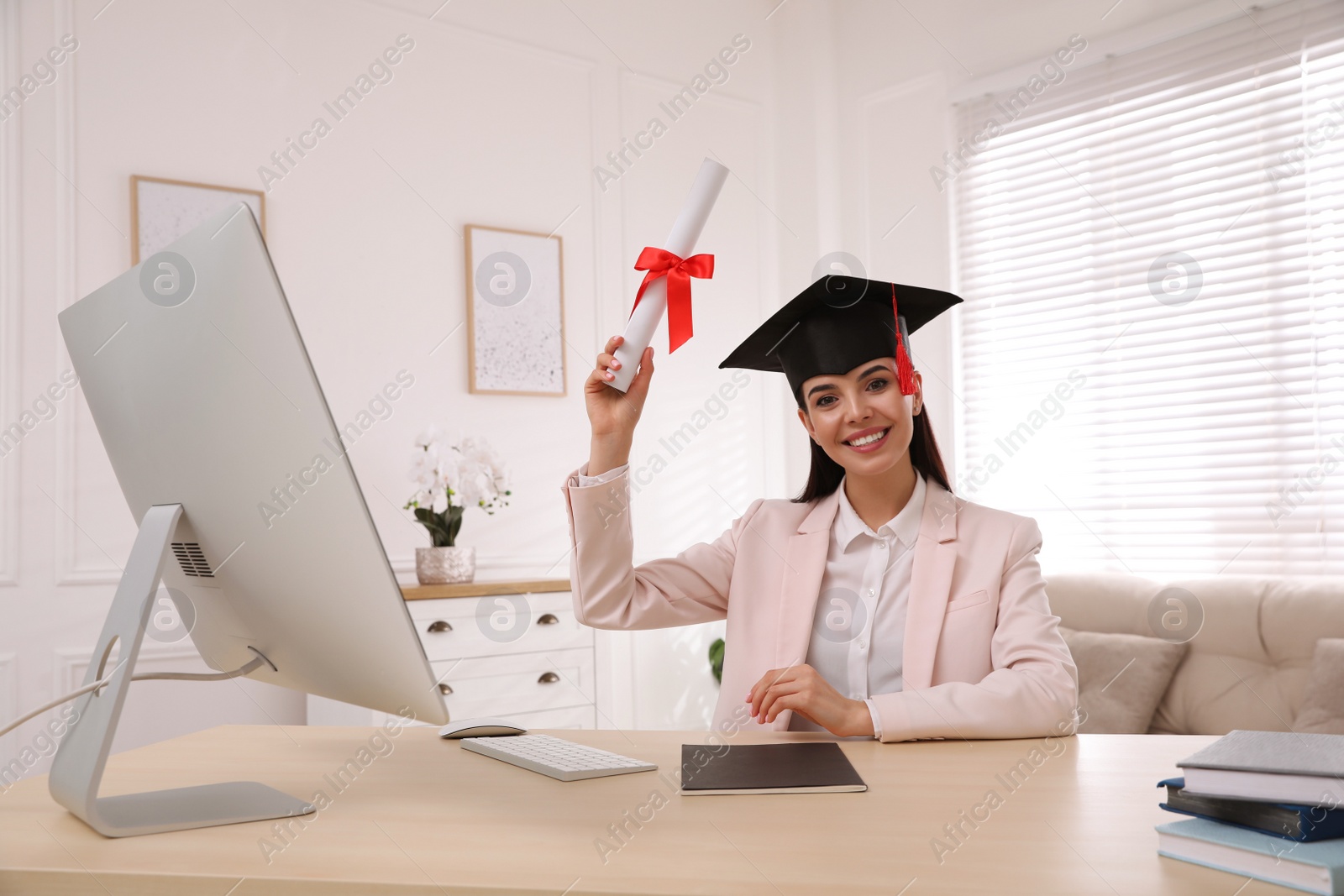 Photo of Happy student with graduation hat and diploma at workplace in office