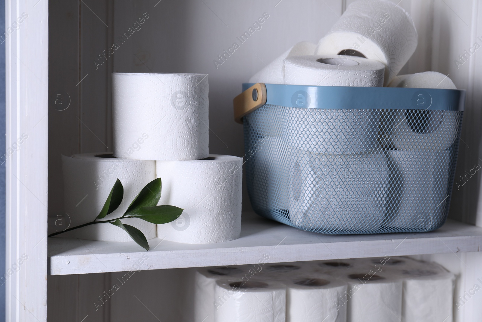 Photo of Toilet paper rolls and green leaves on white shelf