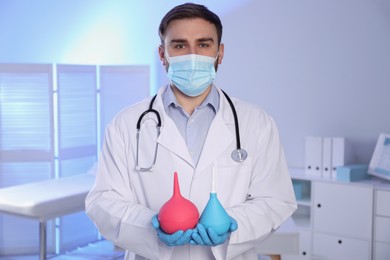 Doctor holding rubber enemas in examination room