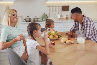 Happy family eating together at table in modern kitchen