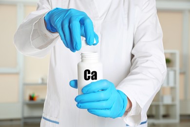 Image of Doctor in medical gloves opening bottle of calcium supplement pills in clinic, closeup